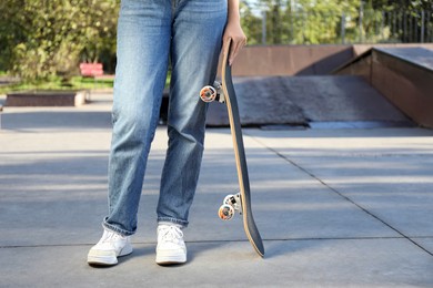 Photo of Woman with modern skateboard in skatepark, closeup. Space for text