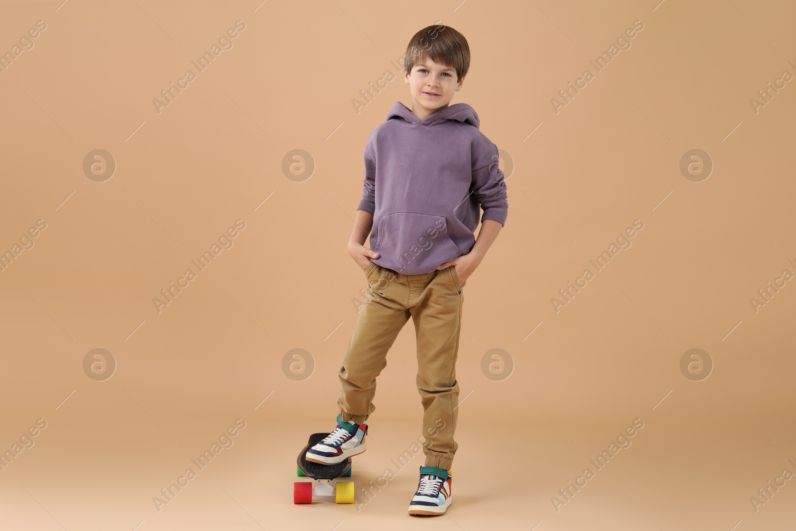 Photo of Little boy with skateboard on beige background