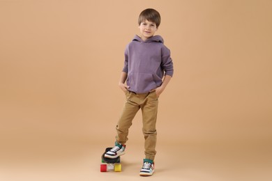 Little boy with skateboard on beige background