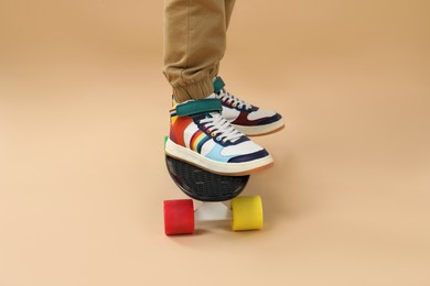 Photo of Little boy with skateboard on beige background, closeup