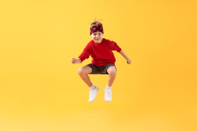 Photo of Happy little boy jumping on yellow background