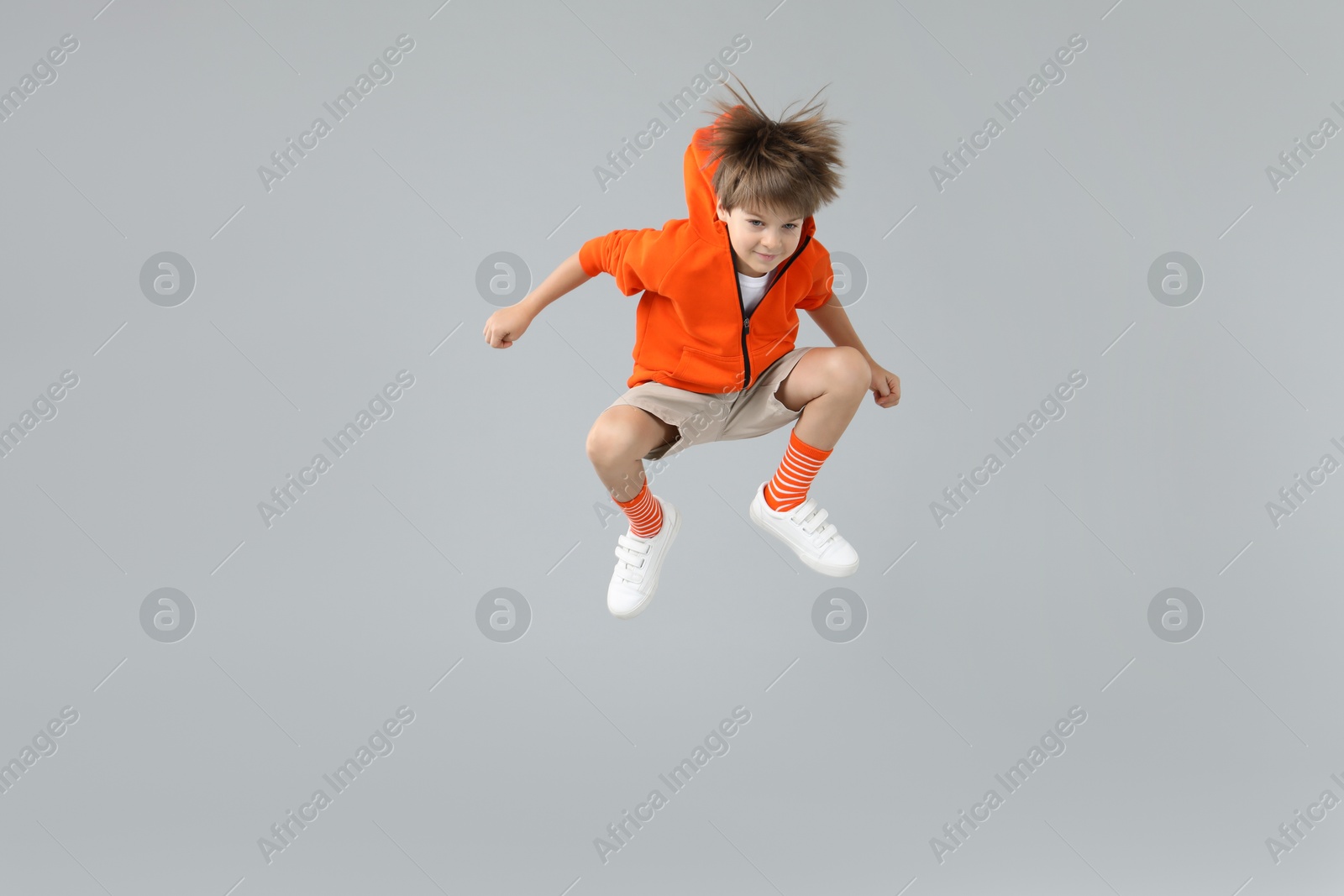 Photo of Happy little boy jumping on light grey background