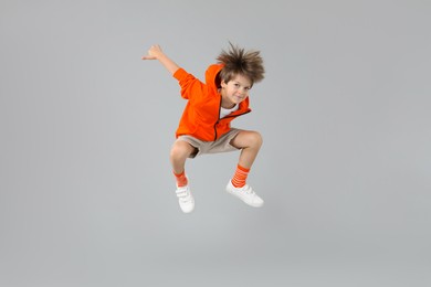 Photo of Happy little boy jumping on light grey background