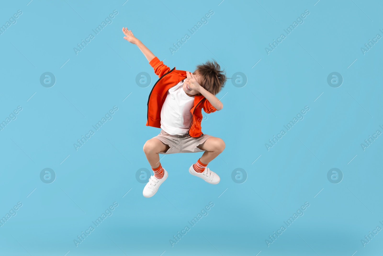 Photo of Happy little boy jumping on light blue background