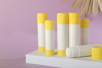 Photo of Glue sticks, podium and dry palm leaf on violet background