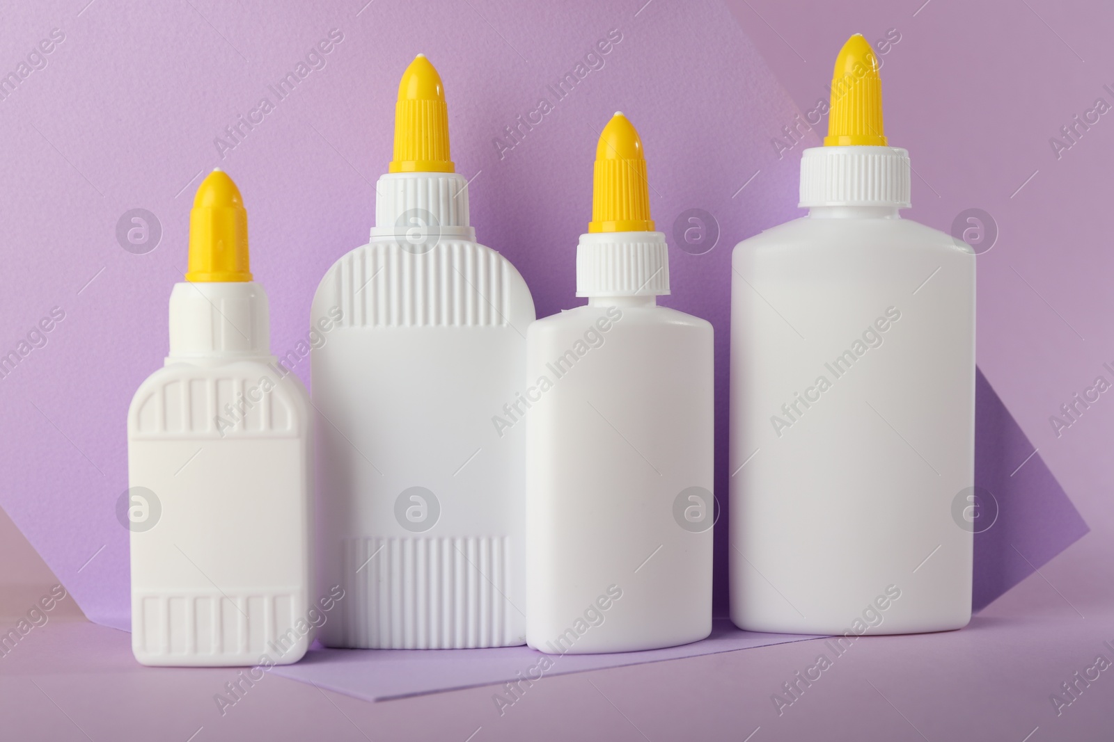 Photo of Many bottles of glue on violet background