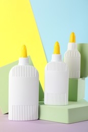 Photo of Bottles of glue and podiums on table against color background