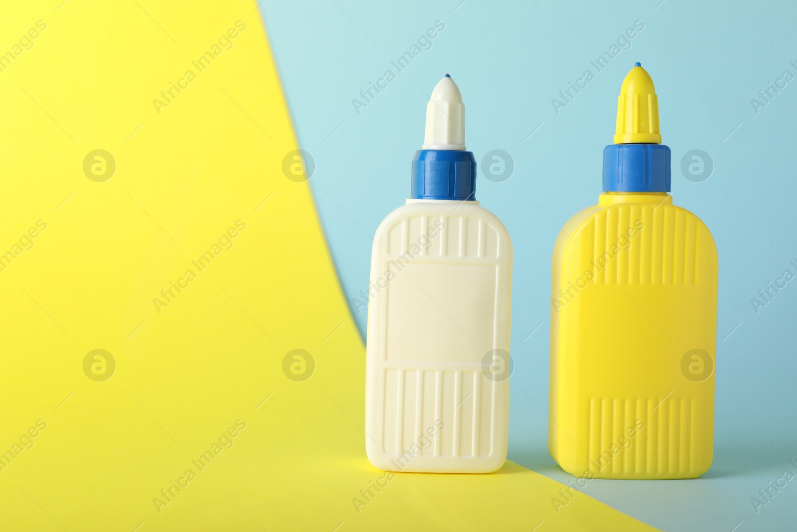 Photo of Two bottles of glue on color background, space for text