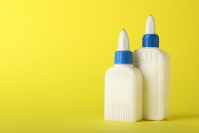 Photo of Two bottles of glue on yellow background, space for text