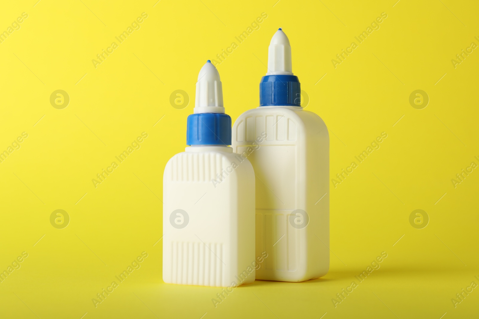 Photo of Two bottles of glue on yellow background