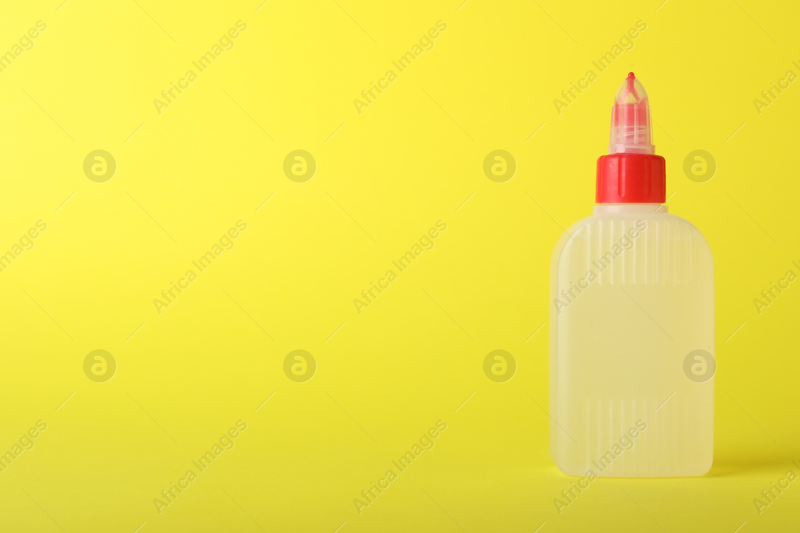 Photo of One bottle of glue on yellow background, space for text