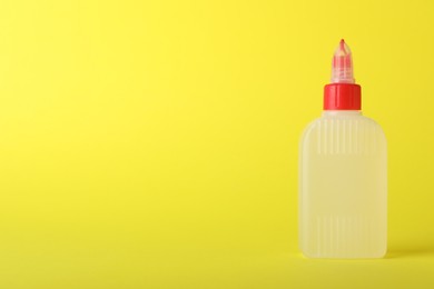 Photo of One bottle of glue on yellow background, space for text