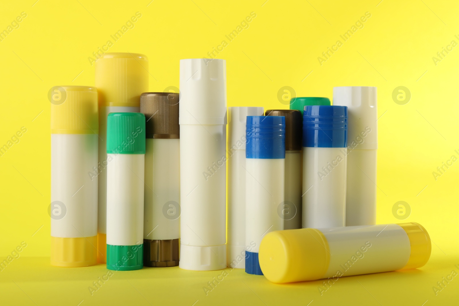 Photo of Many different glue sticks on yellow background