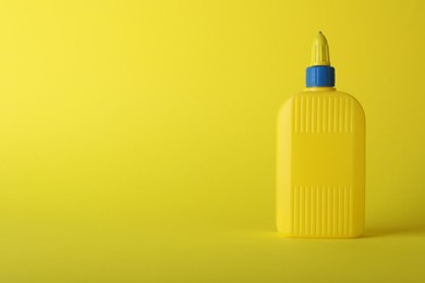 Photo of One bottle of glue on yellow background, space for text