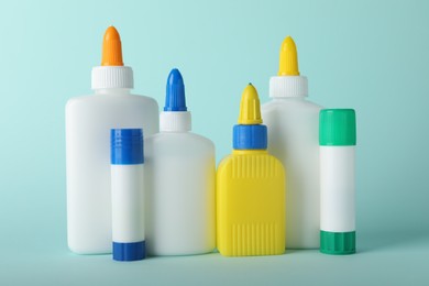 Photo of Bottles and sticks of glue on light blue background