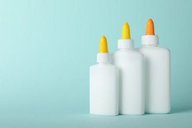 Photo of Bottles of glue on light blue background, space for text