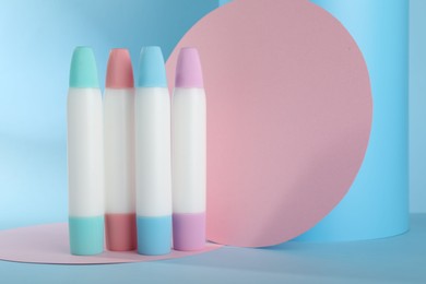 Photo of Many different glue sticks and paper cutouts on light blue background