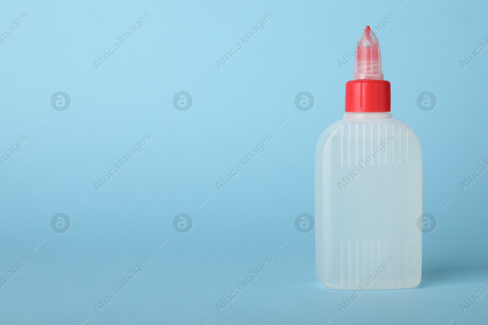 Photo of One bottle of glue on light blue background, space for text