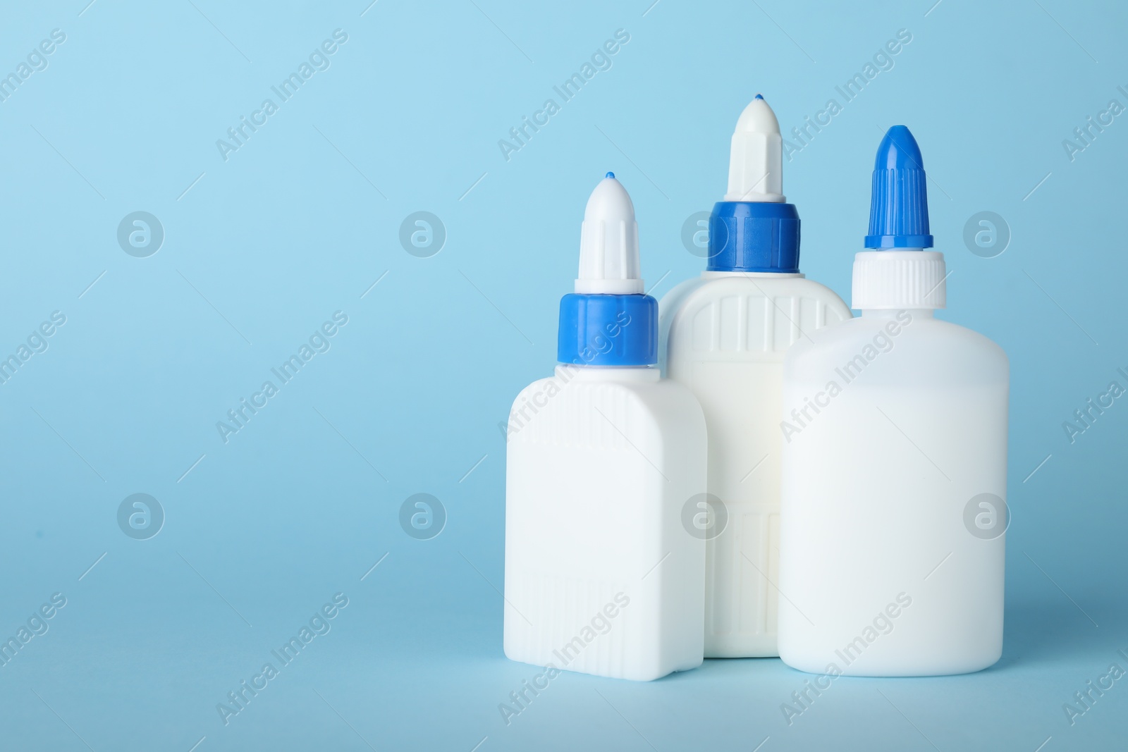 Photo of Bottles of glue on light blue background, space for text