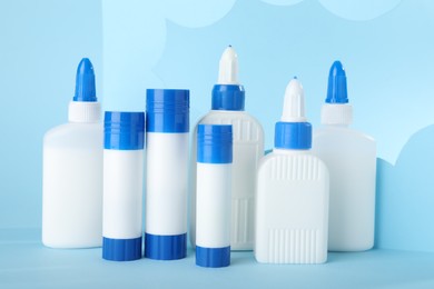 Photo of Bottles and sticks of glue on light blue background