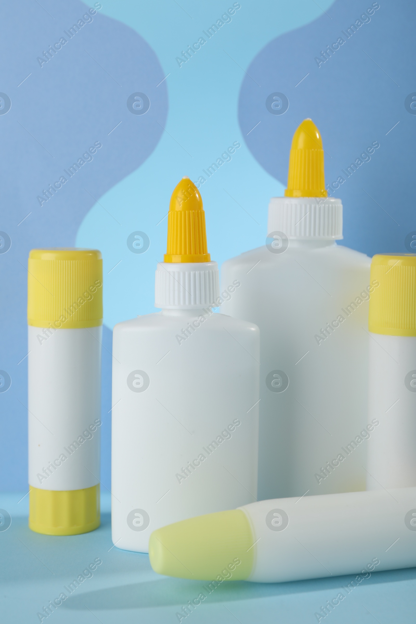 Photo of Different types of glue and paper cutouts on light blue background