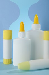 Photo of Different types of glue and paper cutouts on light blue background