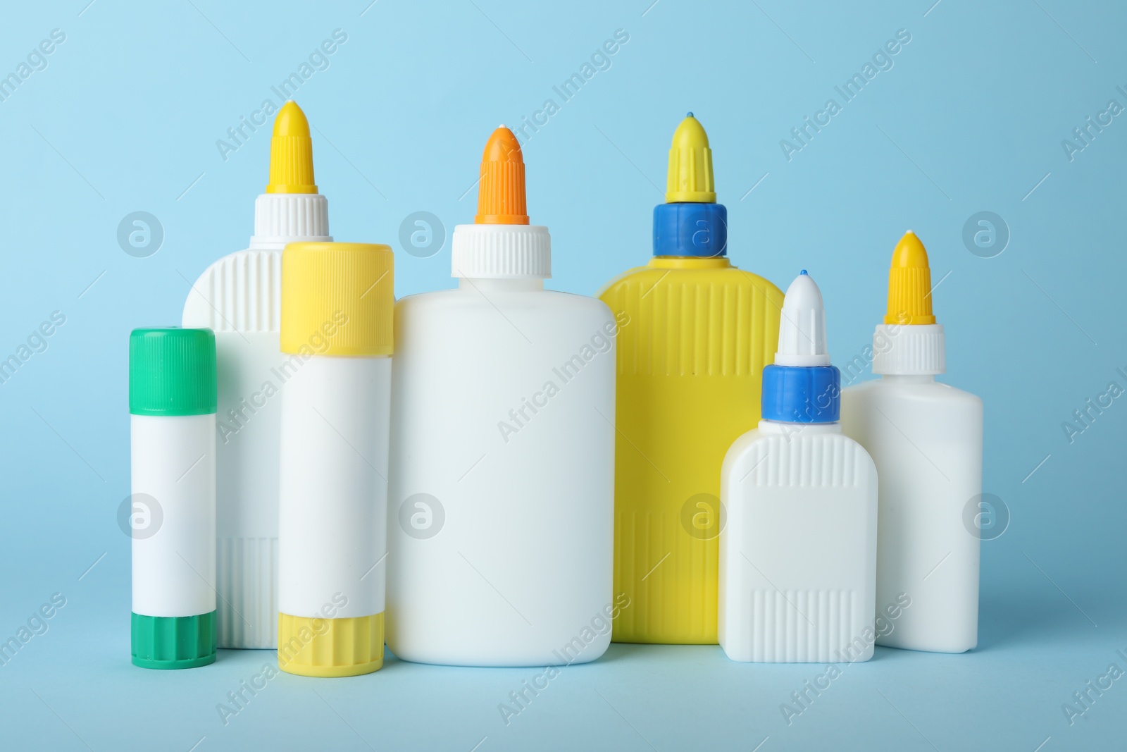 Photo of Bottles and sticks of glue on light blue background