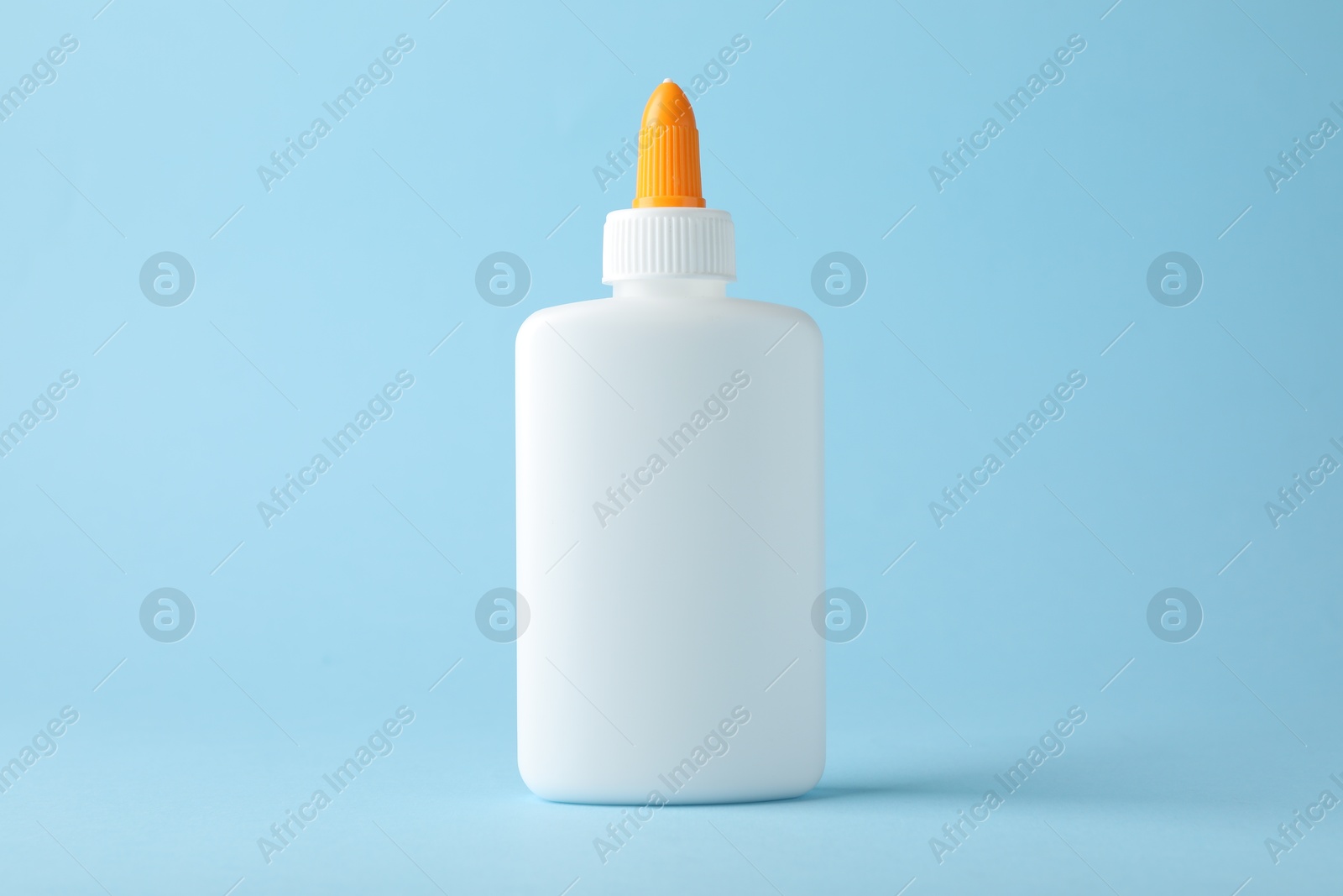 Photo of Bottle of glue on light blue background