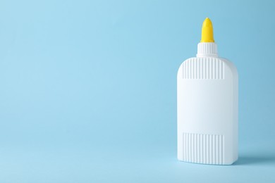 Photo of Bottle of glue on light blue background, space for text