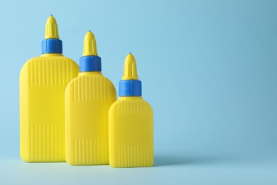 Photo of Bottles of glue on light blue background, space for text