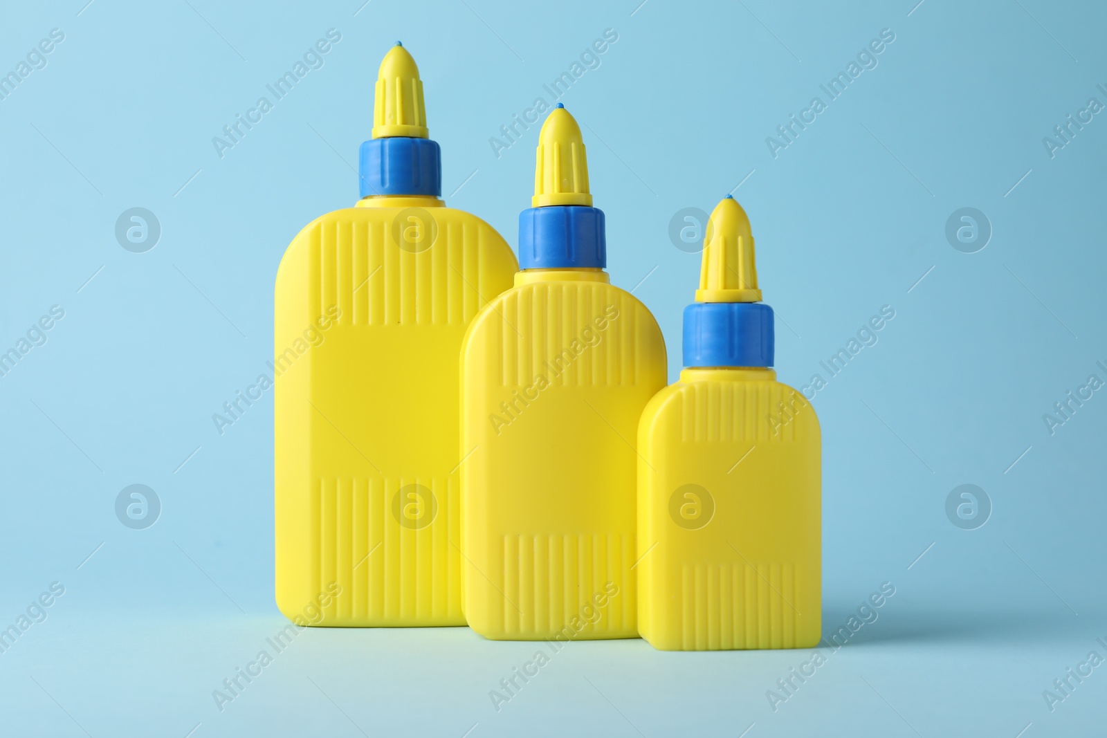 Photo of Bottles of glue on light blue background