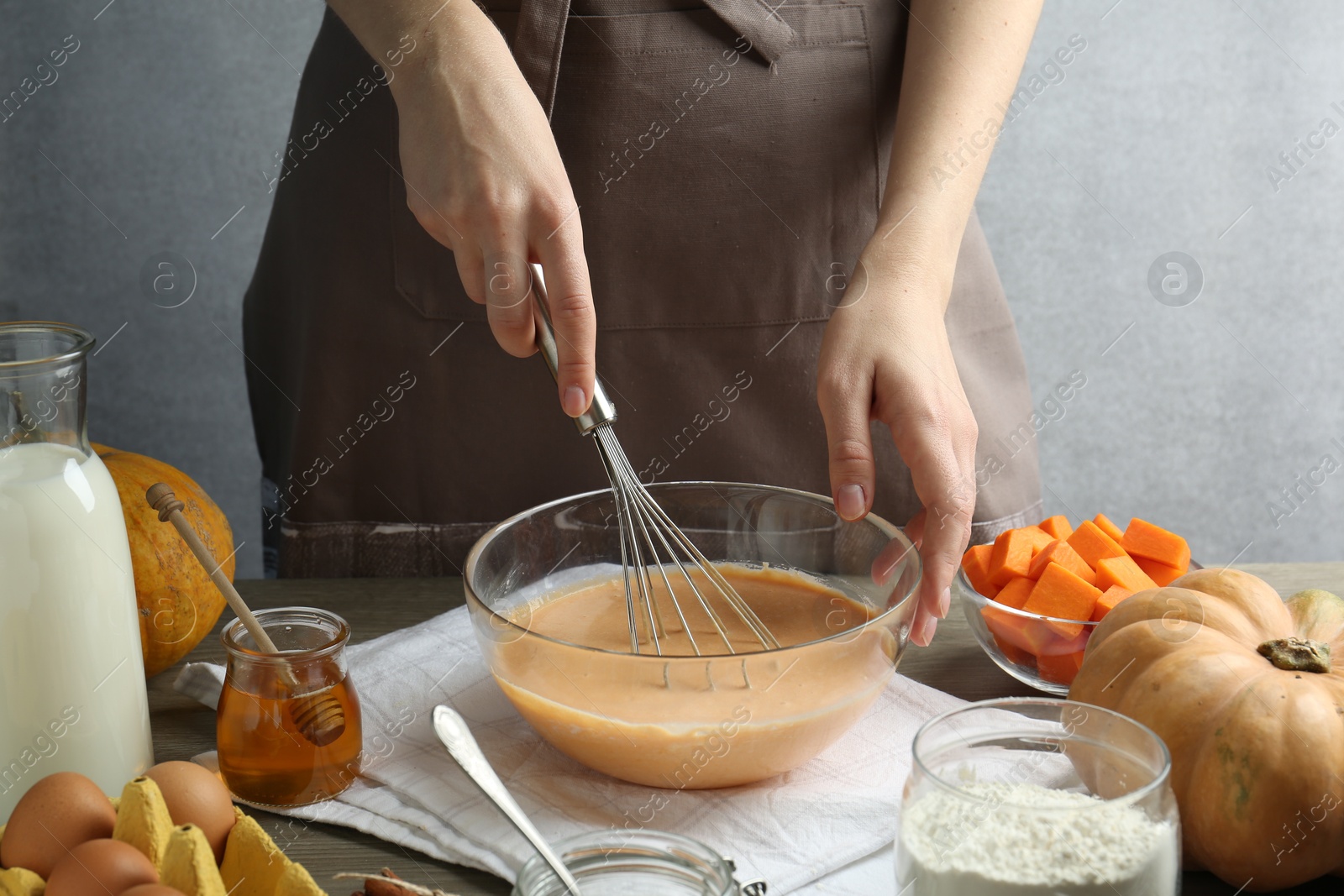 Photo of Making pumpkin pancakes. Woman mixing dough at table, closeup