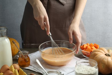 Photo of Making pumpkin pancakes. Woman mixing dough at table, closeup