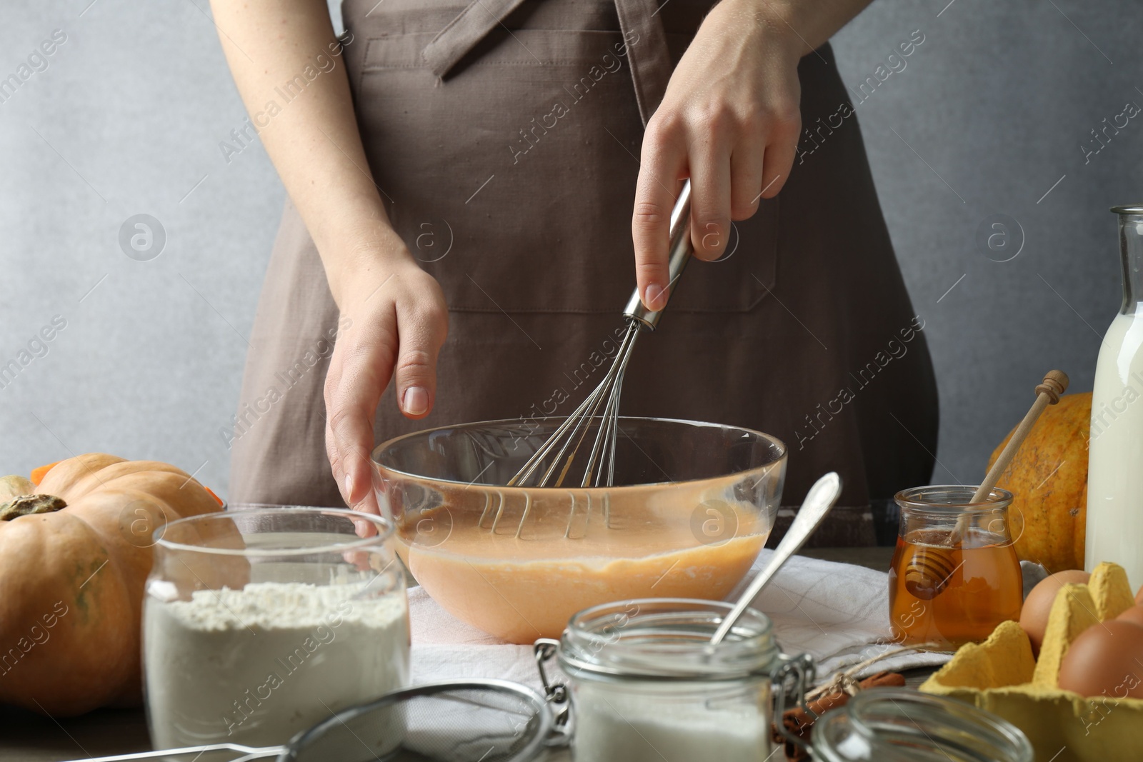 Photo of Making pumpkin pancakes. Woman mixing dough at table, closeup