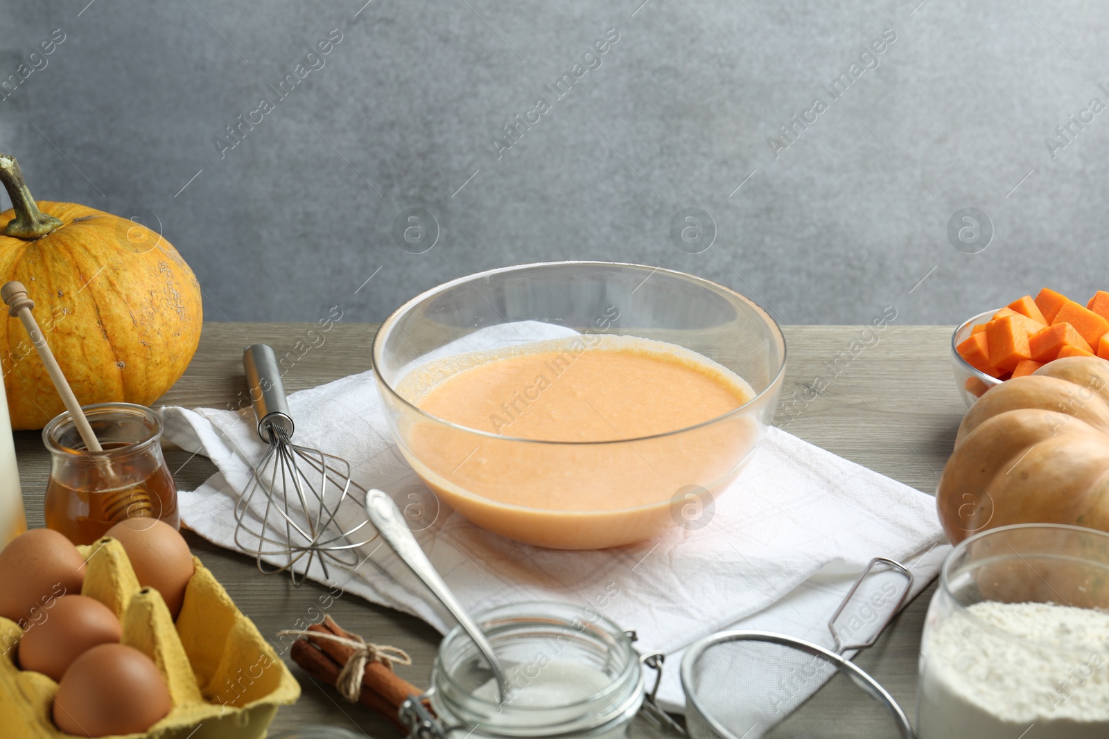 Photo of Bowl with dough and ingredients for pumpkin pancakes on wooden table