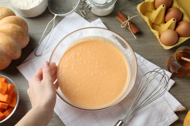 Photo of Woman making pumpkin pancakes at wooden table, top view