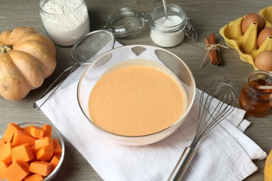 Photo of Bowl with dough and ingredients for pumpkin pancakes on wooden table