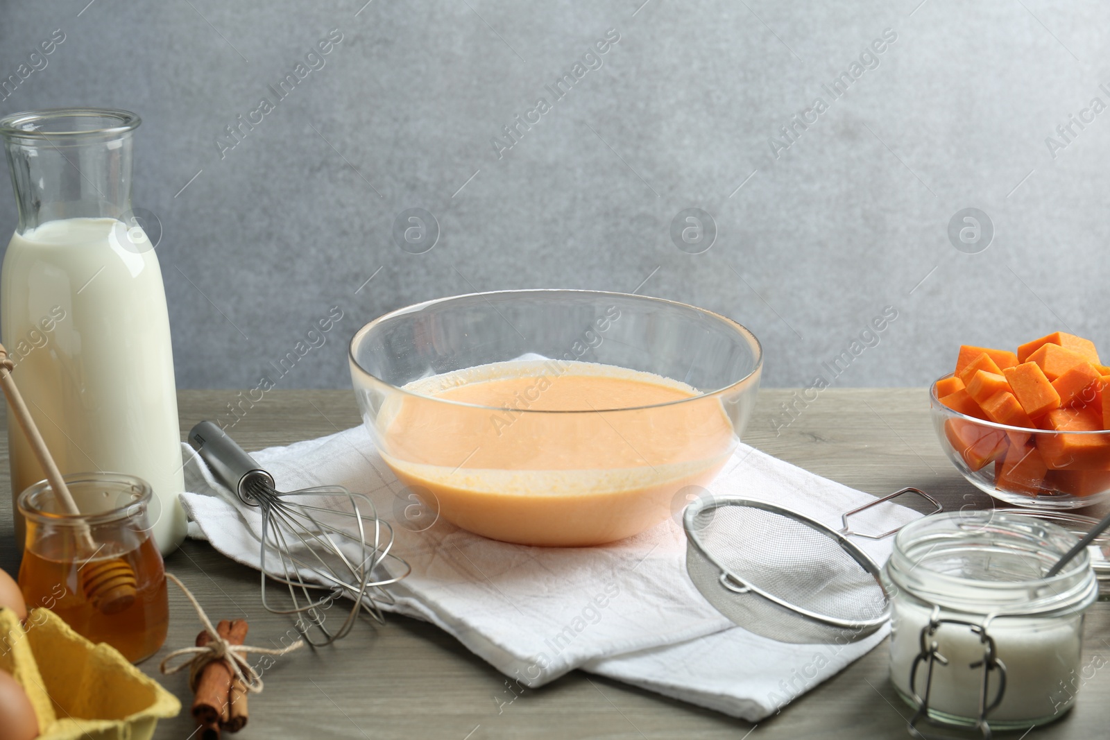 Photo of Bowl with dough and ingredients for pumpkin pancakes on wooden table