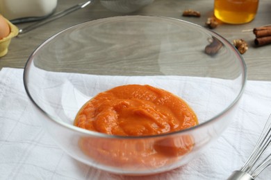 Photo of Bowl with pumpkin puree on wooden table, closeup