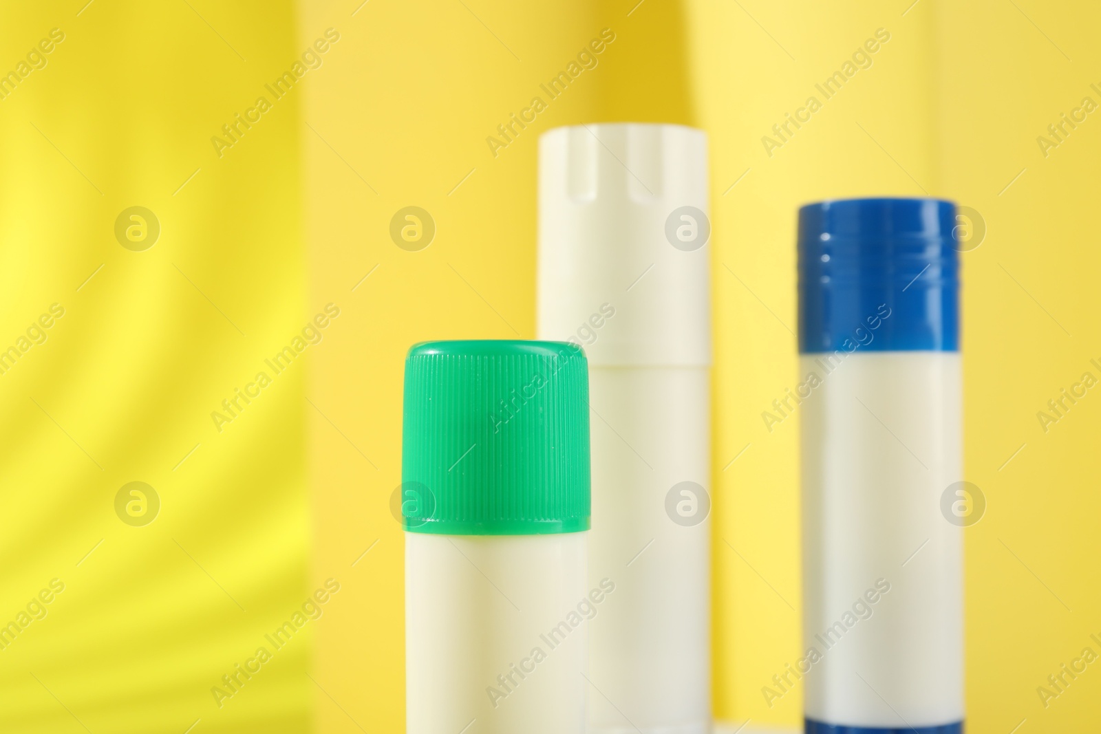 Photo of Sticks of glue on yellow background, closeup. Space for text