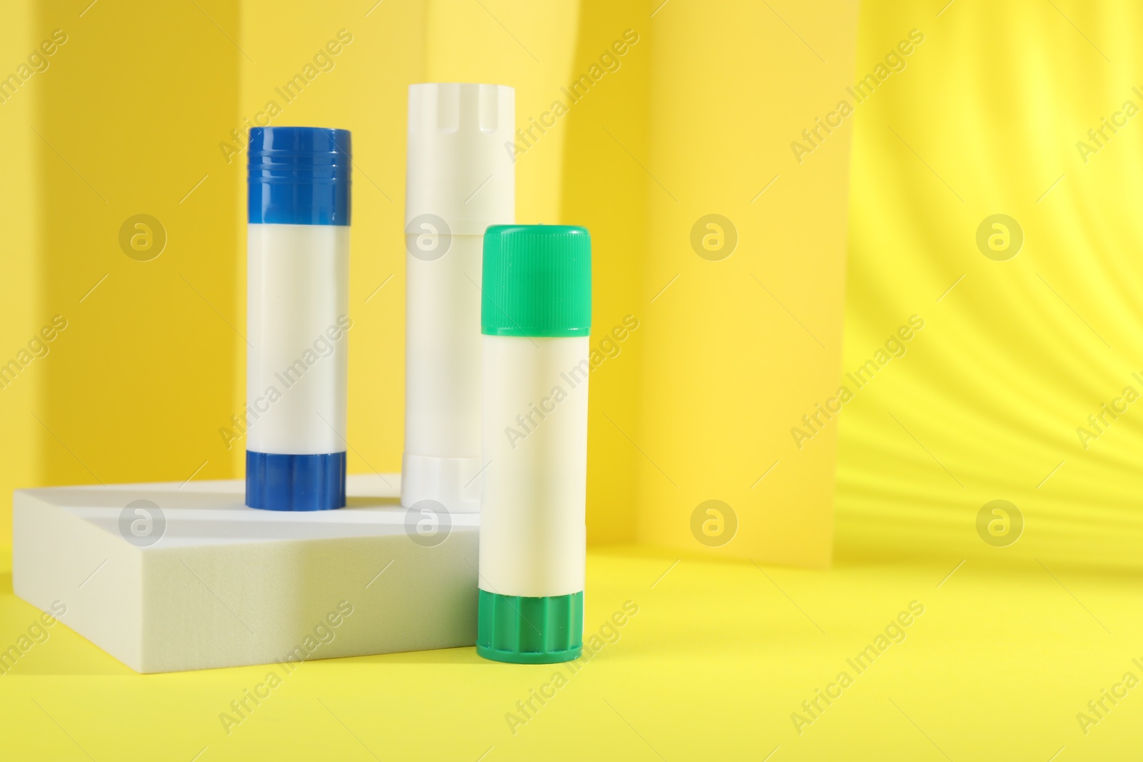 Photo of Sticks of glue on yellow background, space for text