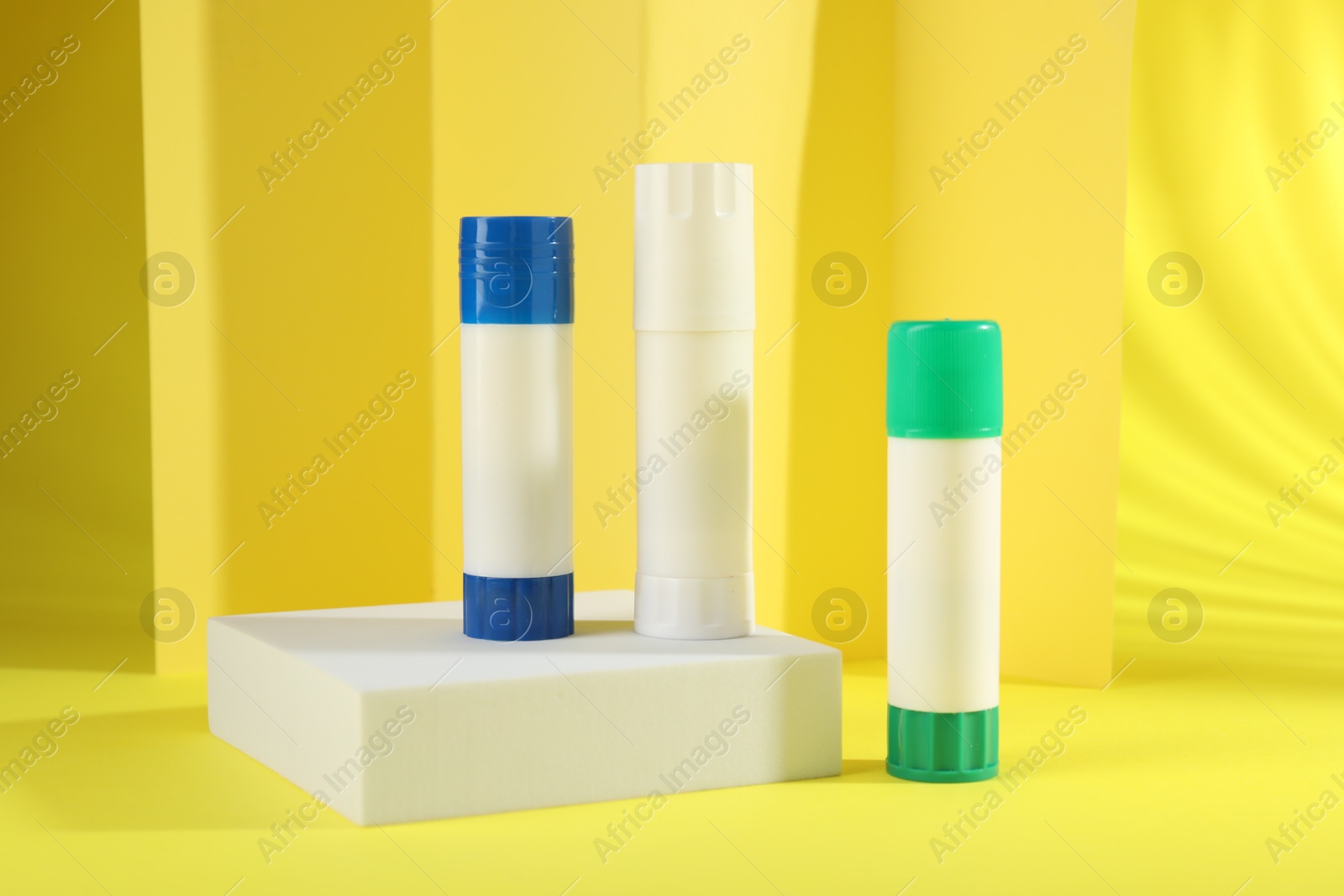 Photo of Sticks of glue on yellow background. School stationery