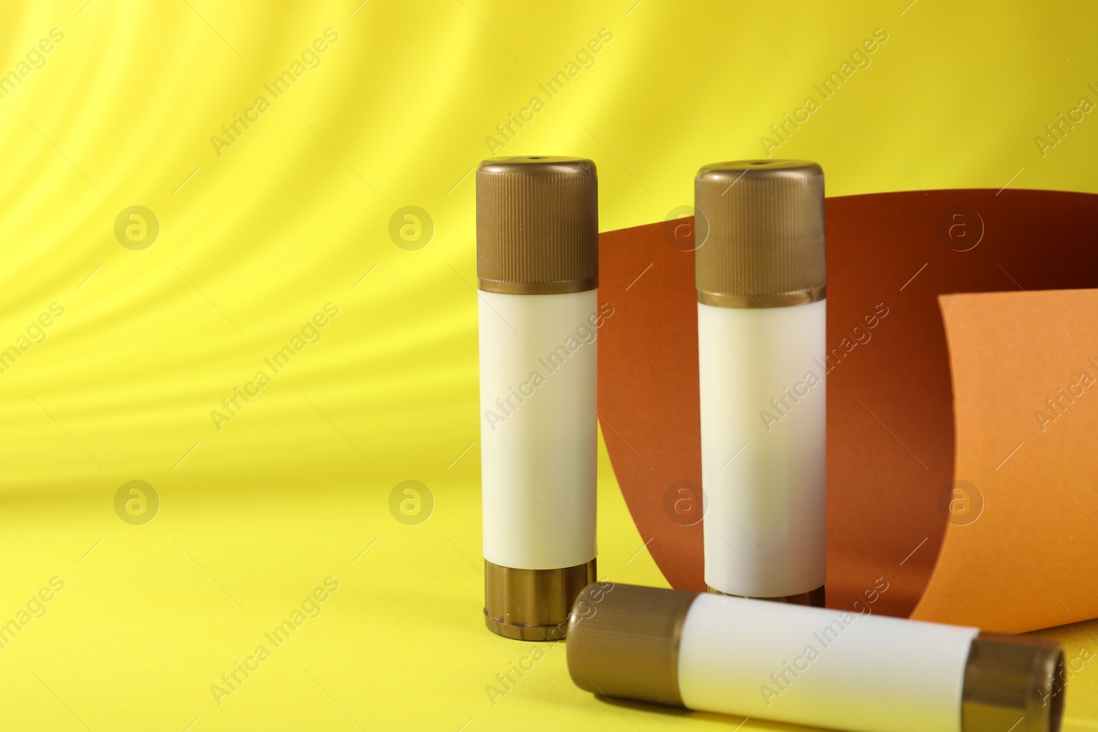 Photo of Sticks of glue on yellow background, space for text