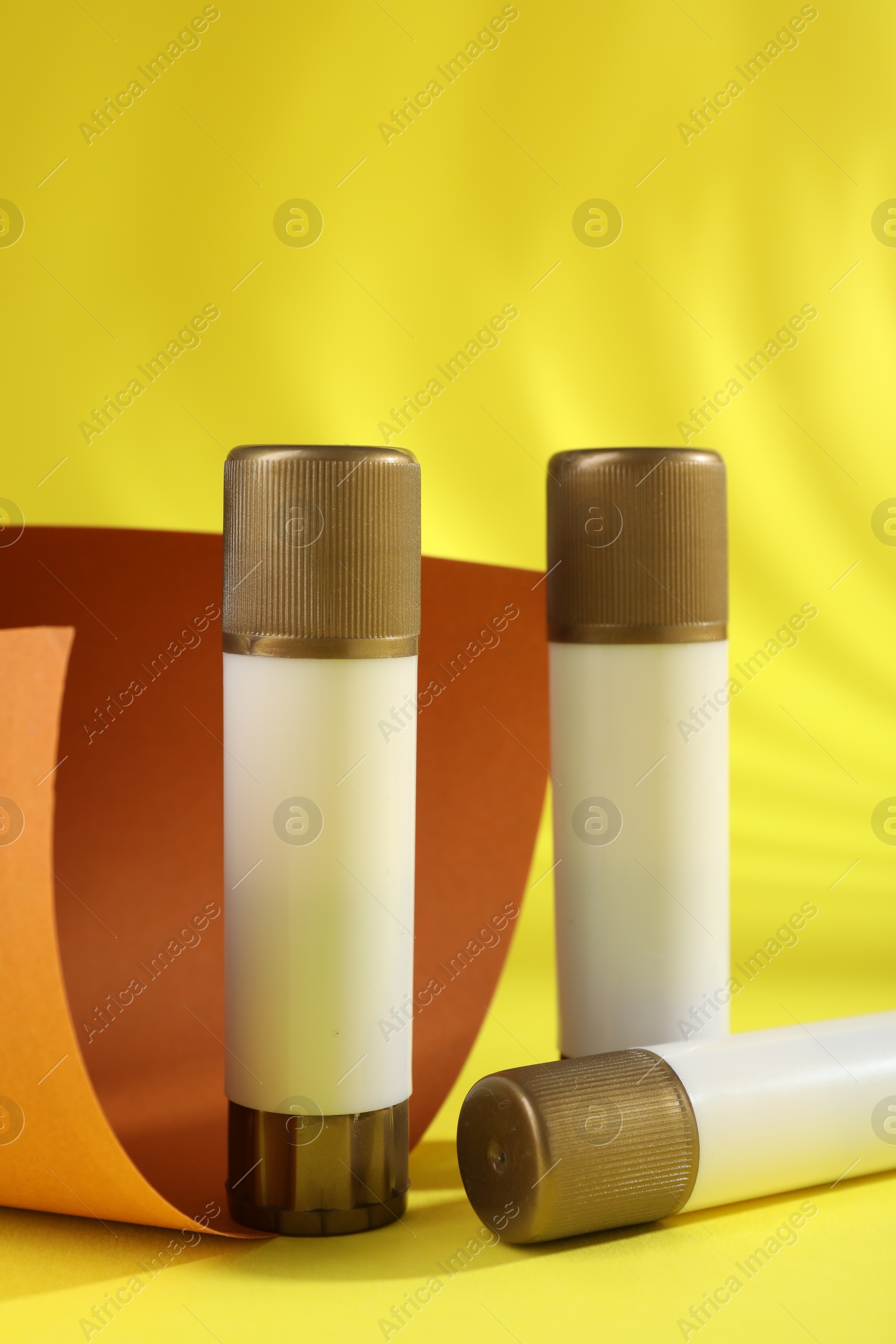 Photo of Sticks of glue on yellow background. School stationery