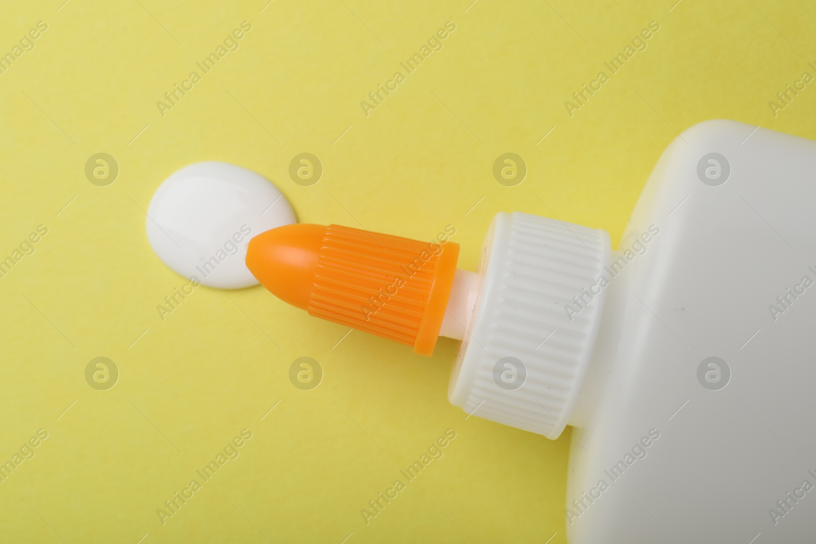 Photo of Bottle of glue on yellow background, top view