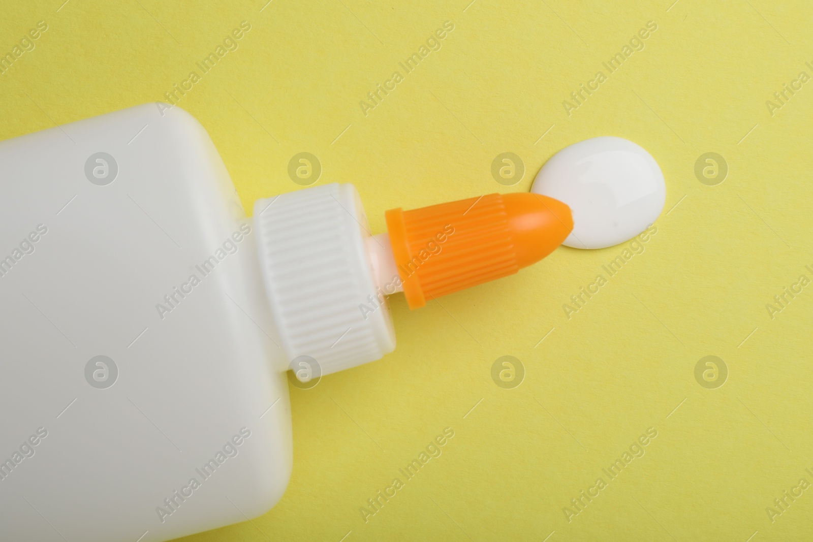 Photo of Bottle of glue on yellow background, top view