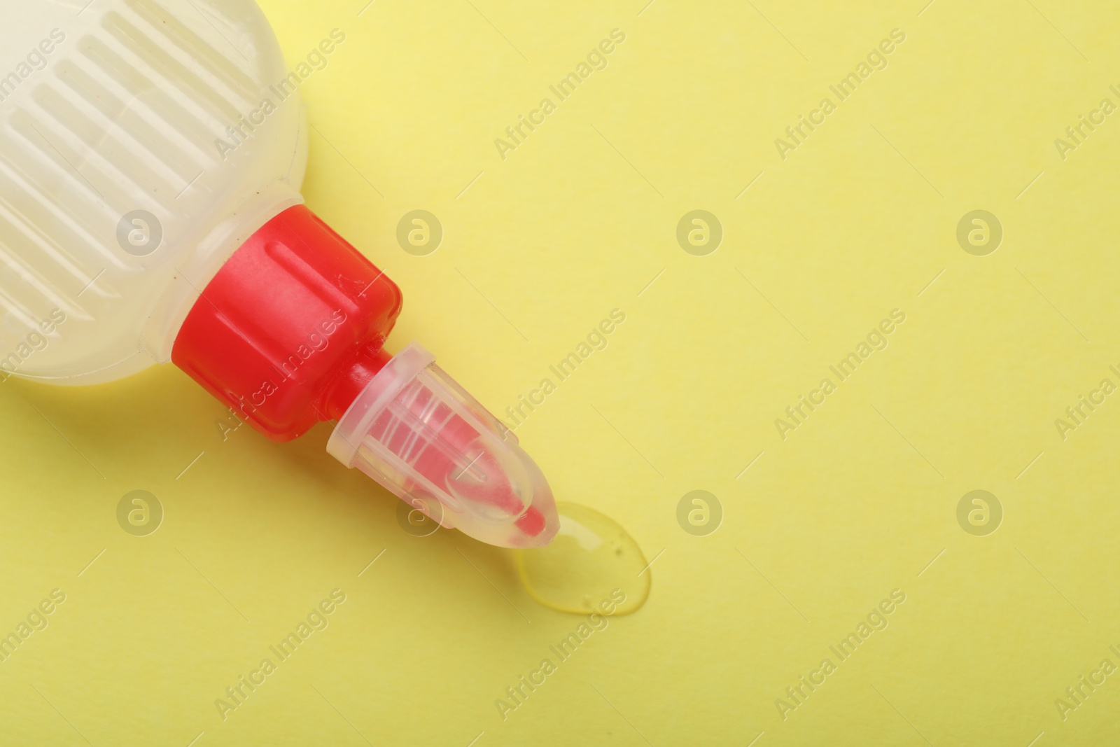 Photo of Bottle of glue on yellow background, top view. Space for text