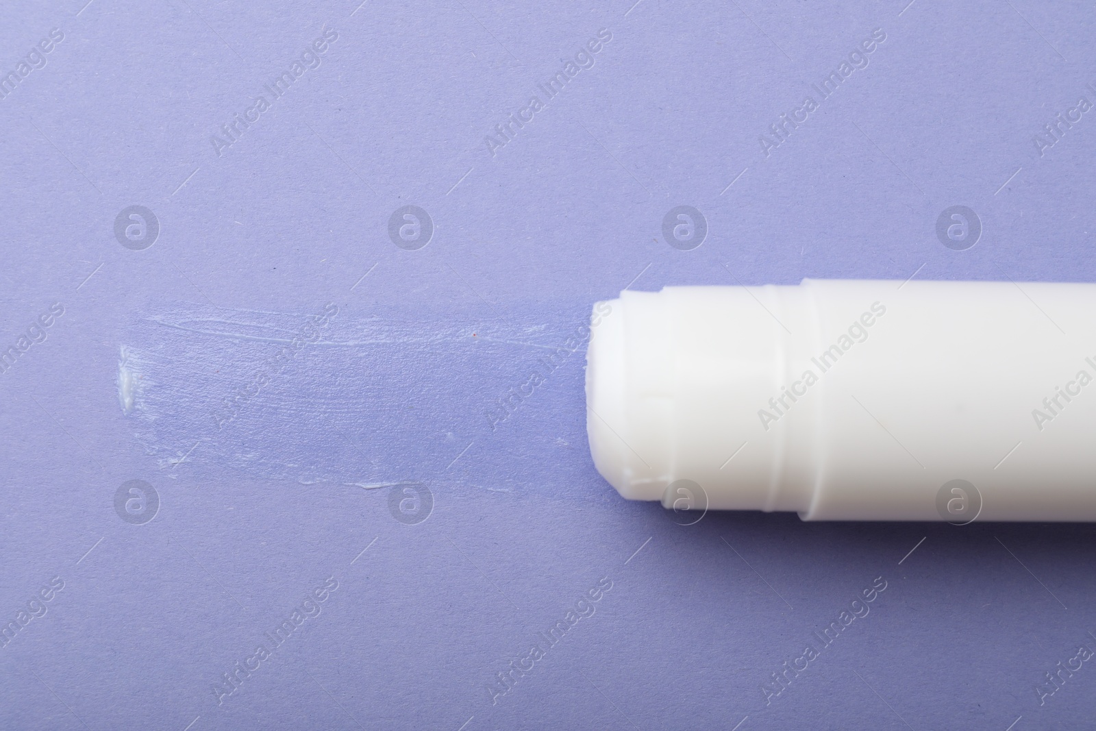 Photo of Stick of glue on violet background, top view. Space for text