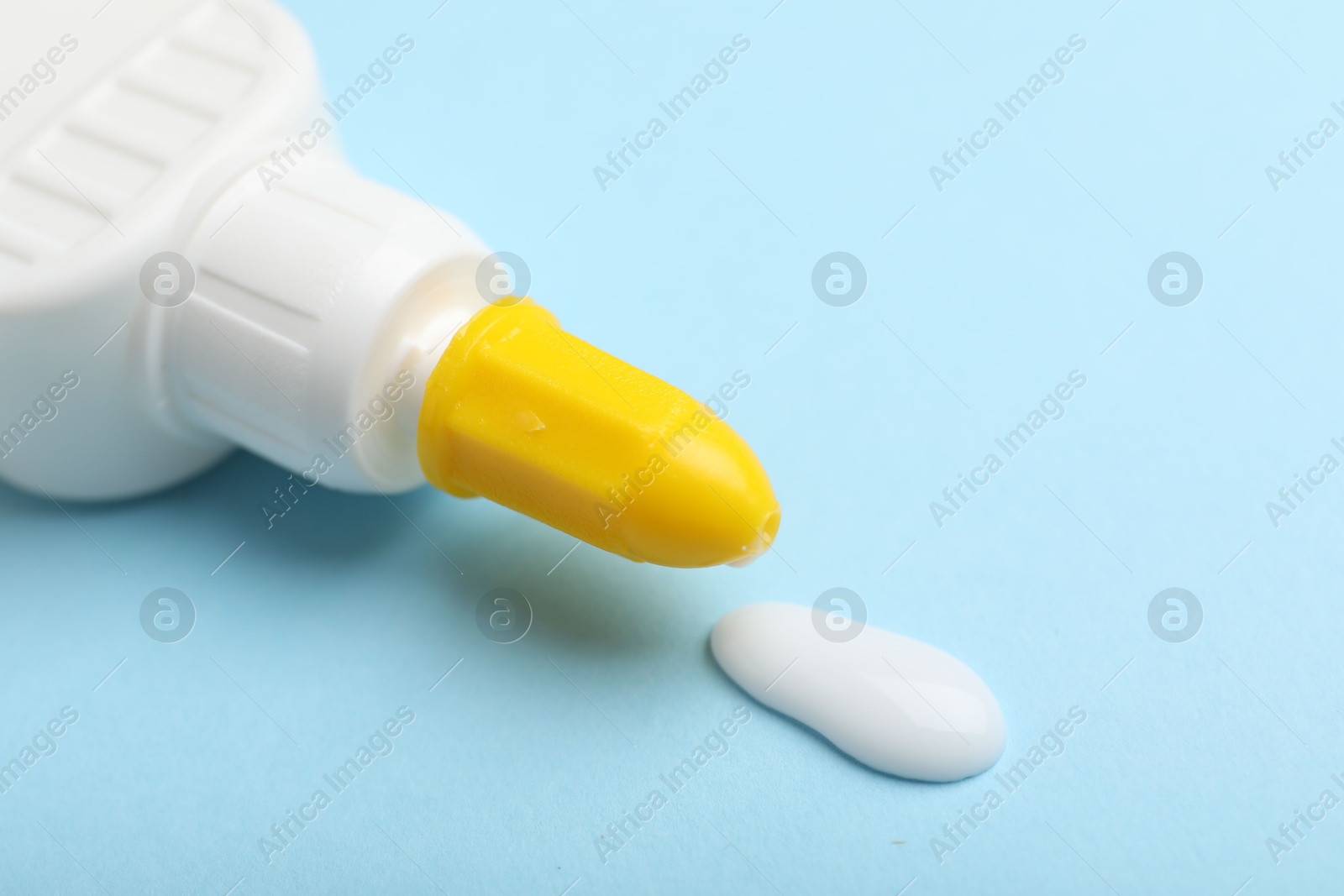 Photo of Bottle of glue on light blue background, closeup. Space for text