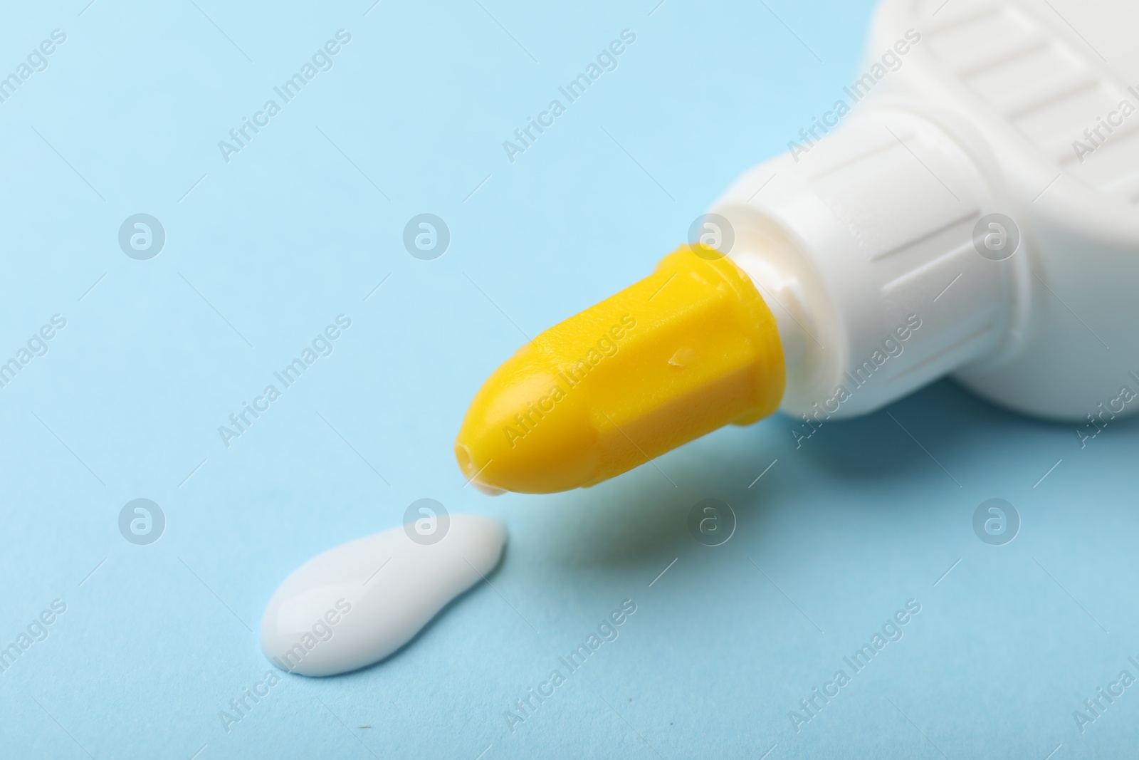 Photo of Bottle of glue on light blue background, closeup. Space for text